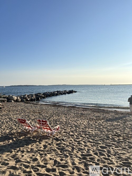 Two chairs are on the beach facing the water.