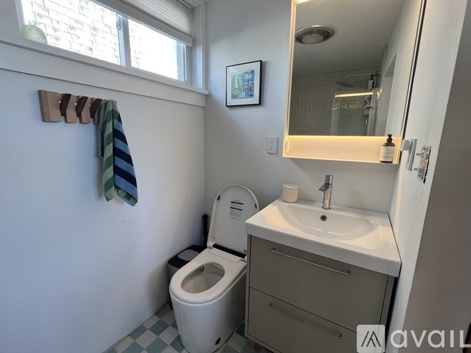 A bathroom with a toilet, sink, and mirror.