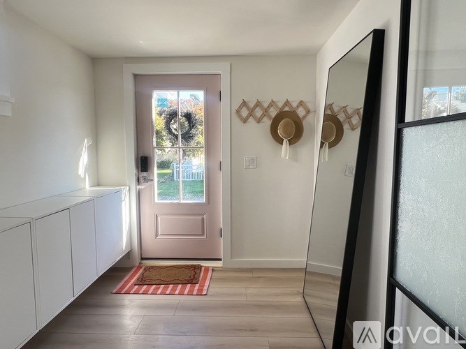 A hallway with a pink door and a mirror on the wall.