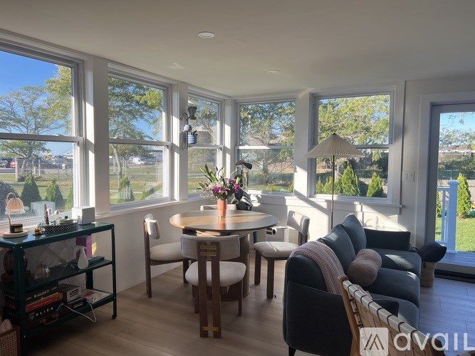 A sunny day in a living room with a table and chairs.