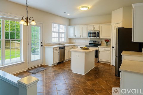 A kitchen with white cabinets and brown tile flooring.