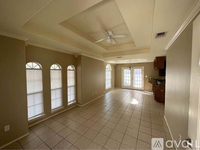 A spacious room with a ceiling fan and large windows.