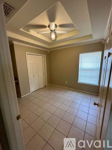 A room with a ceiling fan and tile flooring.