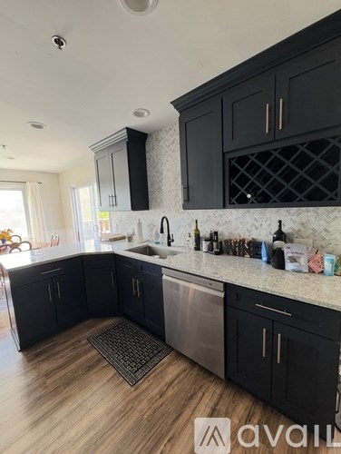 A kitchen with black cabinets and a stainless steel dishwasher.