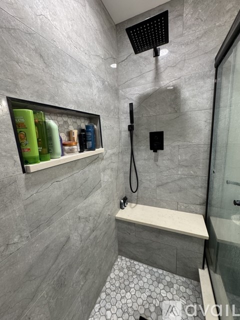 A shower area with a bench and a shelf with bottles.