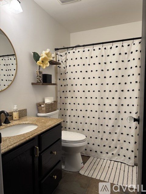 A bathroom with a white shower curtain with black dots.