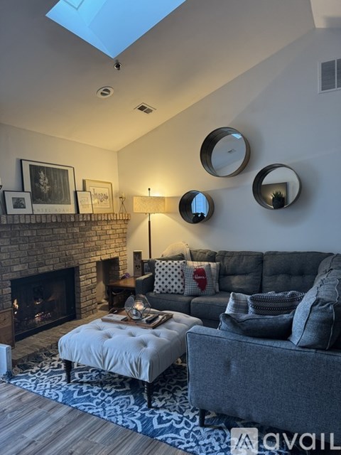 A living room with a fireplace and a grey couch.