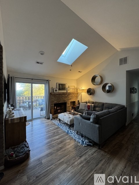 A living room with a grey couch, a fireplace, and a skylight.