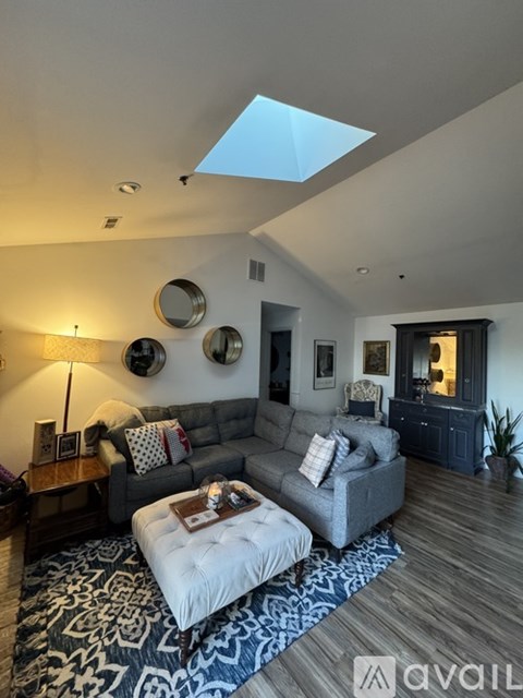 A living room with a grey couch and a skylight.