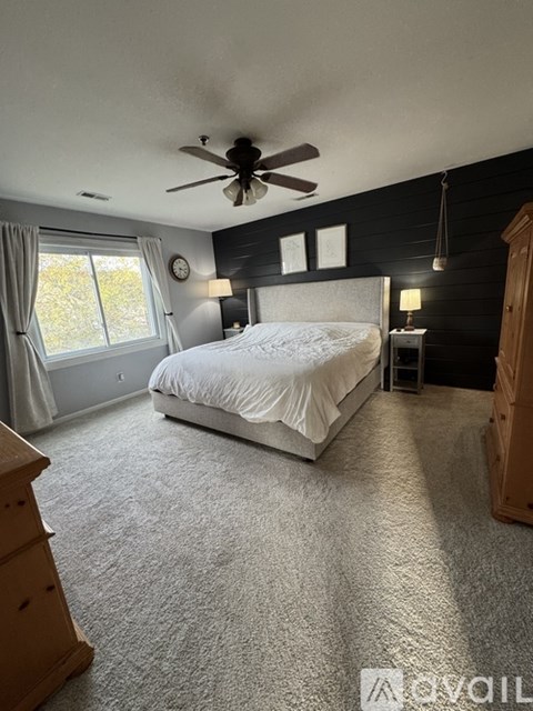 A bedroom with a large bed and a ceiling fan.