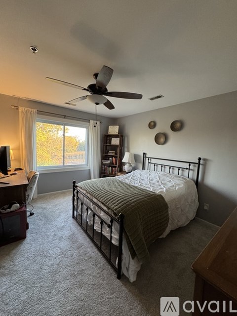 A bedroom with a bed, desk, and window.