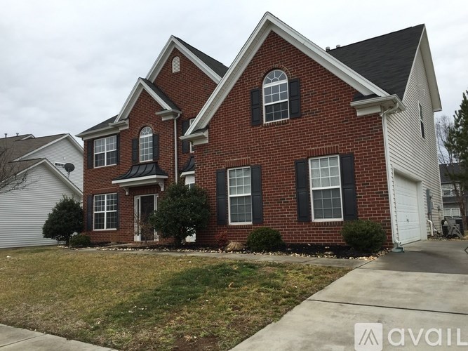 A red brick house with a black roof and white trim.
