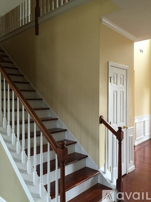 A staircase with a white balustrade and wooden handrail.