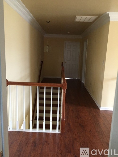 A hallway with a white door and a wooden staircase.