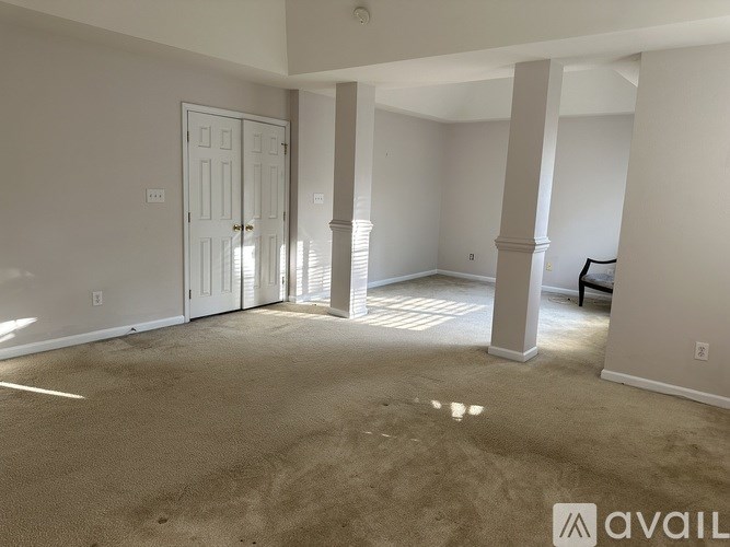 A spacious room with a door, pillars, and a carpeted floor.
