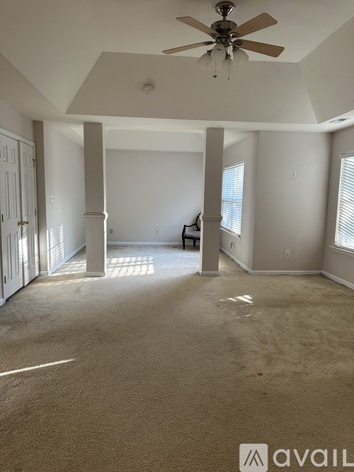 A spacious room with a ceiling fan and carpeted floor.