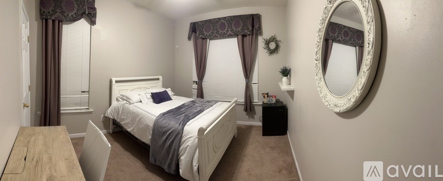 A bedroom with a bed, nightstand, and a round mirror on the wall.