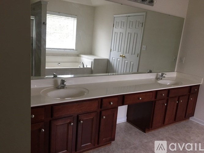 A bathroom with a large mirror and a sink with a cabinet underneath.