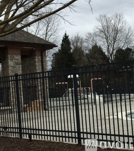 A black fence surrounds a small building with a brown roof.