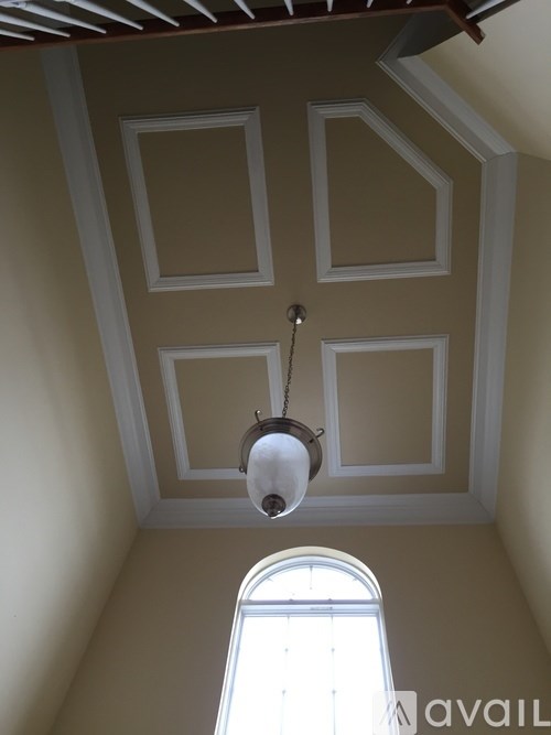 A chandelier hangs from the ceiling in a room with a window.