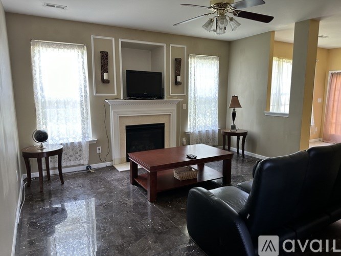 A living room with a fireplace, a chair, and a ceiling fan.