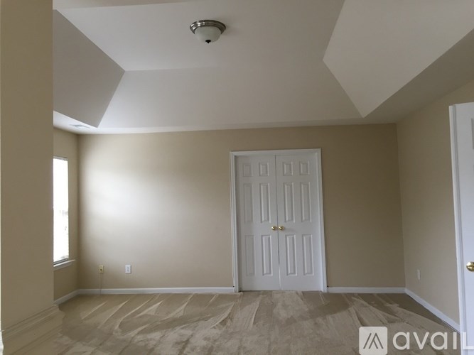 A room with a white door and a window on the left side.