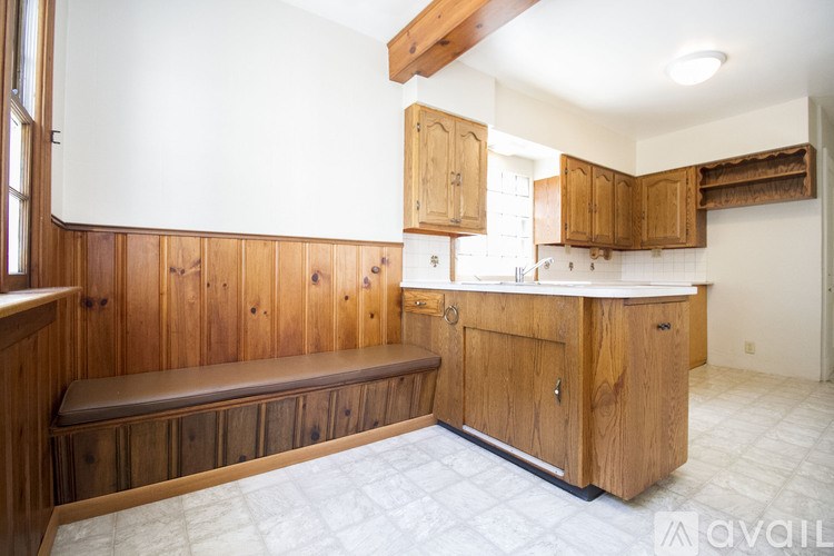 A kitchen with wooden cabinets and a bench seat.