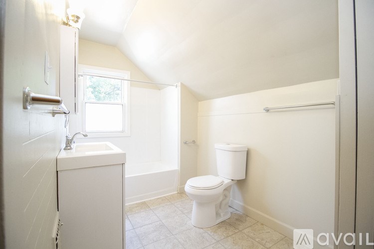 A small white bathroom with a toilet, sink, and a window.
