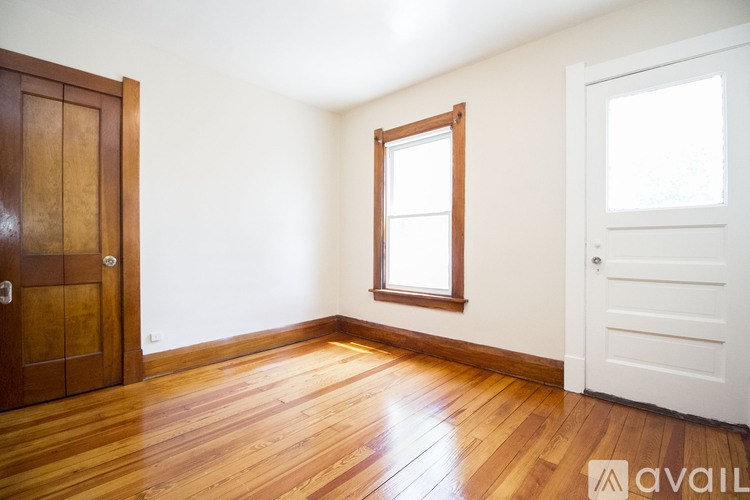 A room with wooden floors and a window with white walls.