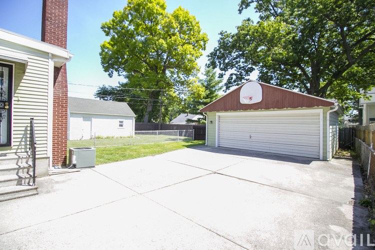 A house with a garage and a tree in the background.
