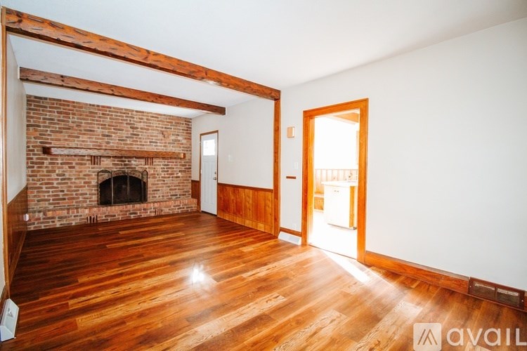 A room with a brick fireplace and wooden floors.