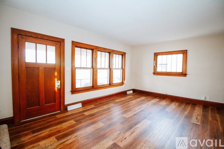 A room with wooden floors and three windows.