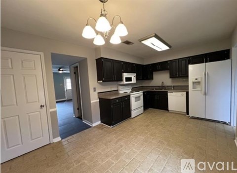 A kitchen with black cabinets and a white refrigerator.
