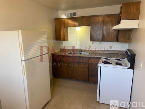 A kitchen with a white fridge, white stove, and wooden cabinets.
