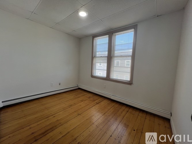 A room with wooden flooring and a window with blinds.