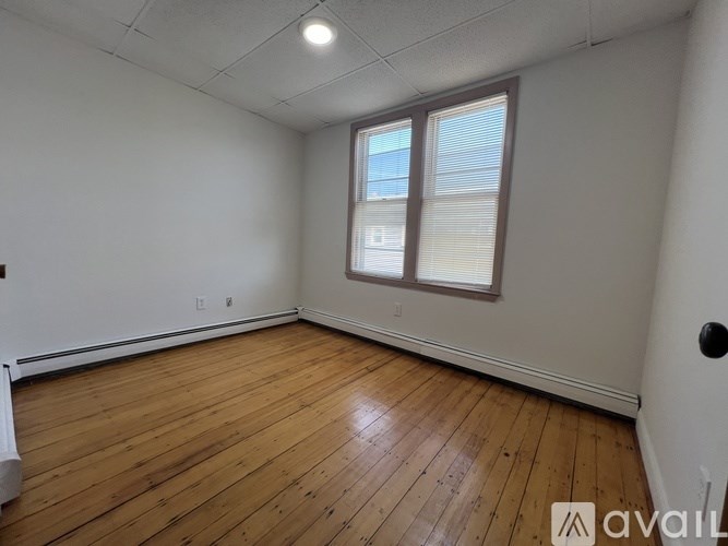 A room with wooden flooring and a window with blinds.