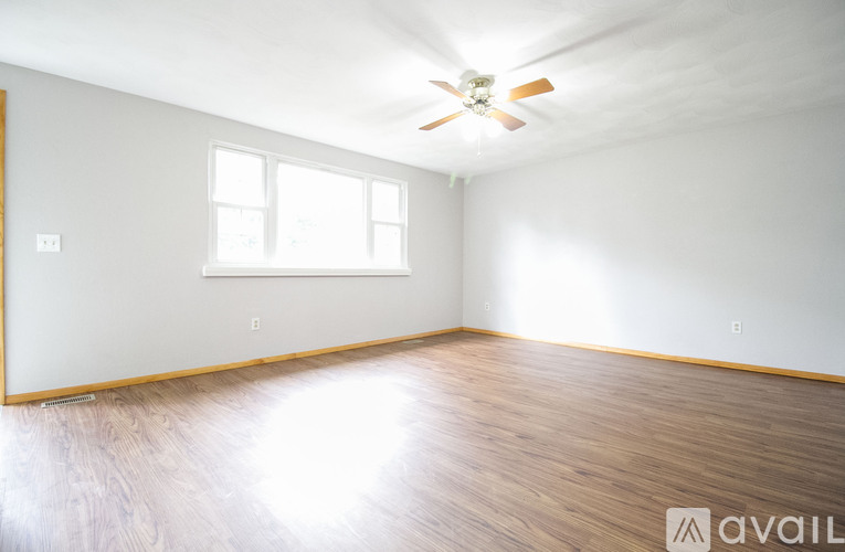 A room with a ceiling fan and wooden flooring.