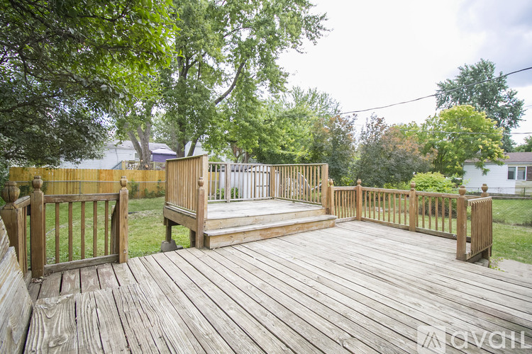 A wooden deck with a railing and steps leading to a grassy area.