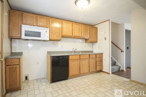 A kitchen with wooden cabinets and a black dishwasher.