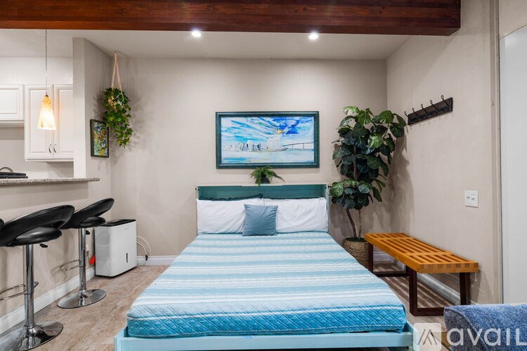 A bedroom with a blue bedspread and a painting on the wall.