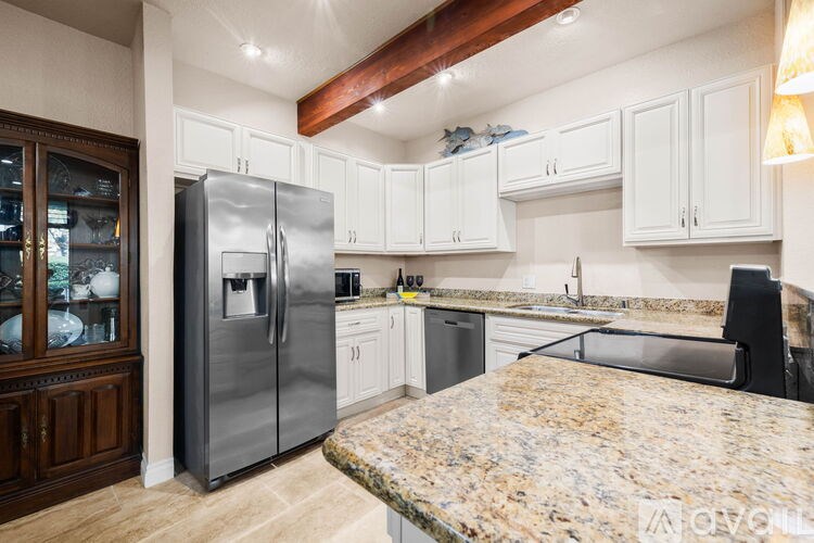 A kitchen with a granite countertop and a stainless steel refrigerator.