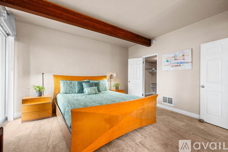 A bedroom with a bed, nightstand, and a painting on the wall.