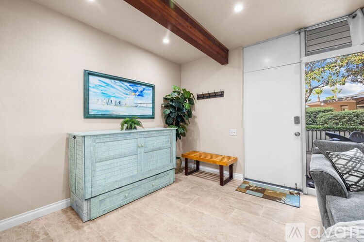 A room with a blue cabinet, a bench, and a painting on the wall.
