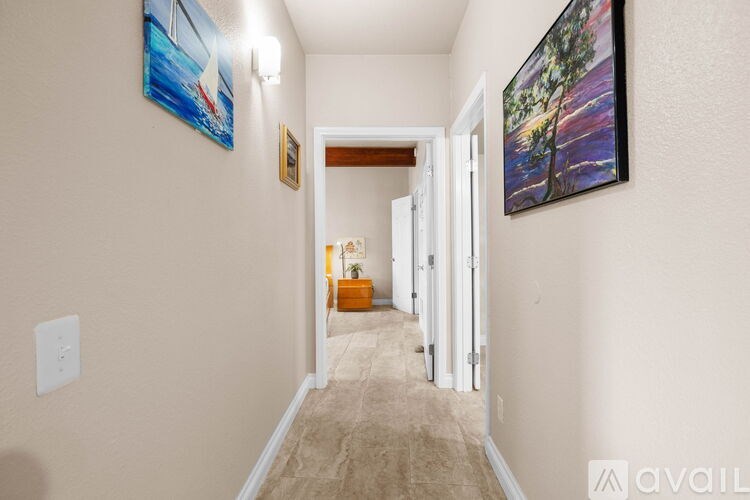A hallway with a painting on the wall and a light switch on the wall.