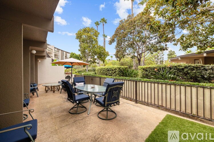 A patio with chairs and a table is surrounded by a fence and trees.