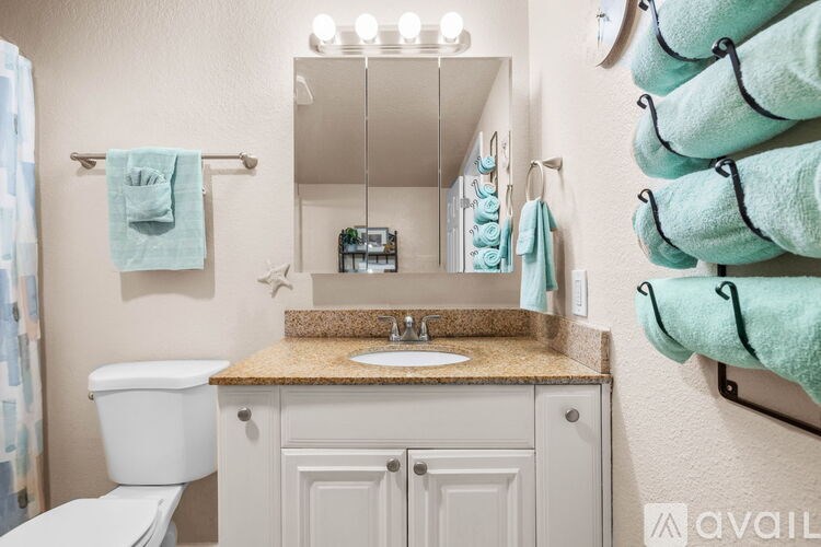 A bathroom with a white toilet, sink, and cabinets.