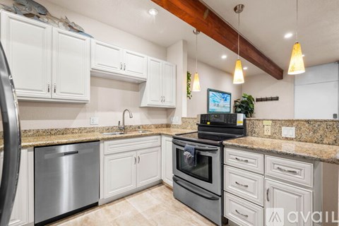 A kitchen with a black stove top oven and white cabinets.
