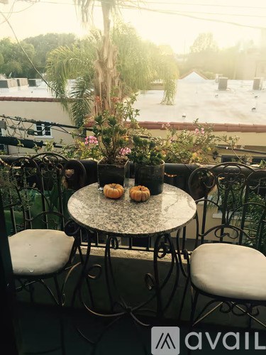 A table with chairs and flowers on it with a view of the rooftops.