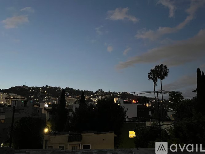 A cityscape at dusk with the skyline illuminated by streetlights.