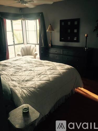 A bedroom with a bed, dresser, and window.